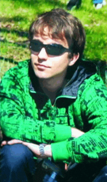 a young man wearing sunglasses and a green jacket with a pattern on it