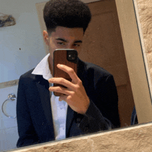 a man in a suit takes a picture of himself in the mirror