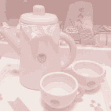 a pink tea set with two cups and a teapot