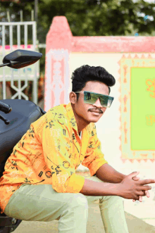 a man wearing sunglasses and a yellow shirt sitting on a bike