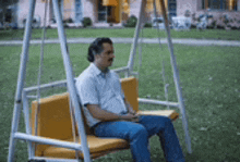 a man is sitting on a yellow swing .