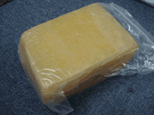 a block of cheese is wrapped in plastic on a blue carpet