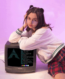 a girl kneeling next to a sharp brand television