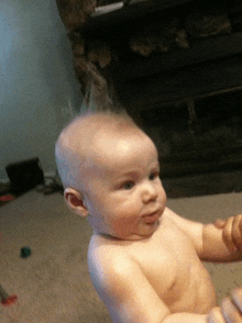 a baby with a mohawk is sitting on the floor