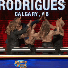 a group of people giving each other a high five in front of a sign that says rodriques calgary ab