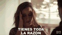 a woman is holding her head and the words tienes toda la razon are above her