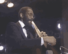 a man in a suit and tie is playing a trumpet on stage