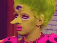 a woman with green hair has three eyes on her forehead