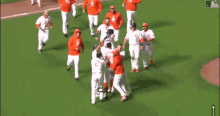 a group of men are standing on a baseball field . one of the men is wearing an orange hat .