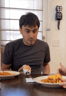 a man sitting at a table with a plate of food and a clock on the wall that says ' ee '