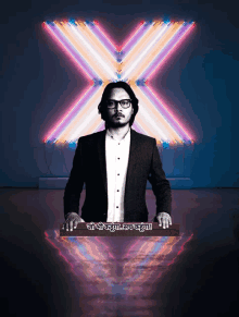 a man in a suit stands in front of a neon sign that says ' x '