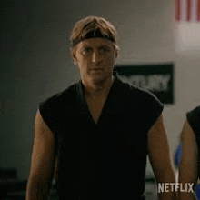 a man wearing a headband and a black shirt is standing in a gym .