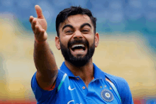 a man with a beard is wearing a blue shirt that says ' cricket ' on it