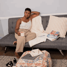 a woman sits on a couch with a cup of coffee and books on the floor including one titled ' a woman '