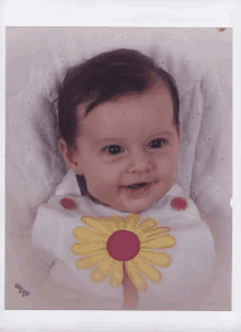 a baby girl wearing a bib with a yellow flower on it