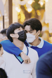 a man wearing a mask is hugging another man wearing a name tag that says ' a ' on it