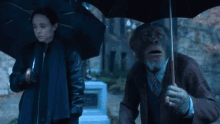 a chimpanzee is holding an umbrella next to a woman holding an umbrella .