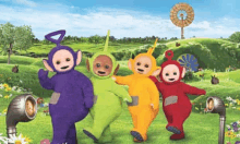 a group of teletubbies standing next to each other in a grassy field .