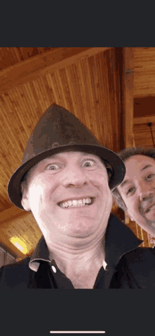 two men are posing for a picture and one has a hat on