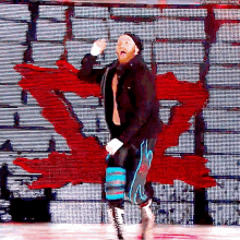 a wrestler is standing on a stage in front of a large screen with a red canadian flag behind him .