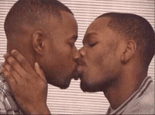 two men are kissing each other in front of a striped background .