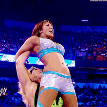 a female wrestler holds a male wrestler up in the air during a match