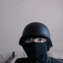 a person wearing a helmet and a black mask looks at the camera