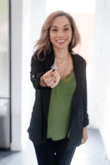 a woman in a green top and black jacket holds a key