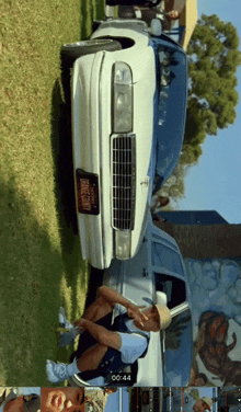 a man sits in front of a white car with a license plate that says longcounty