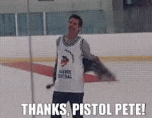 a man is standing on a ice rink with his arms outstretched and saying `` thanks , pistol pete '' .