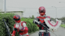 two red power rangers are standing next to each other on a street .