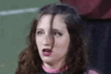 a close up of a woman making a funny face while watching a soccer game .