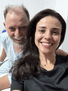 a man and a woman are posing for a picture and the woman is wearing a black shirt