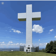 a man stands in front of a very large white cross