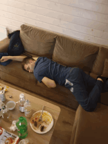 a man is laying on a couch with a bag of chicken noodle soup on the table