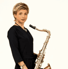 a woman in a black dress holds a saxophone in her right hand