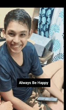 a young boy is smiling while sitting on a bed with the words always be happy above him