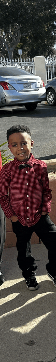 a young boy wearing a red shirt and black pants is sitting on the ground