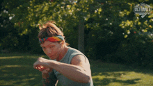 a woman with a bandana on her head is standing in a field with her hands in her fist .