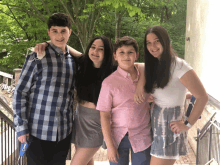 a boy in a plaid shirt stands next to two girls in pink shirts