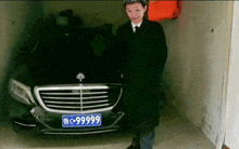 a man stands in front of a mercedes with a license plate that says 6666