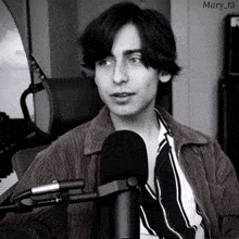 a black and white photo of a young man in front of a microphone with the name mary_t3 on the bottom right