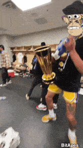 a man holding a trophy in a locker room with a picture of a monkey behind him that says bit apes