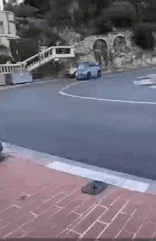 a model car is driving down a street next to a brick curb .