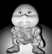 a black and white photo of a doll wearing a polka dot shirt