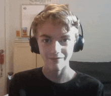 a young boy wearing headphones and a black shirt is smiling for the camera .