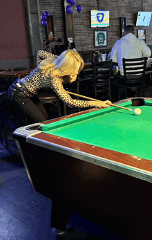 a woman playing pool in a bar with a jersey that says 23 on it