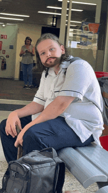 a man with a fake beard sits on a bench next to a backpack