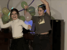 two girls are dancing with glow in the dark balloons and glow in the dark headphones