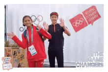 a boy and a girl are posing for a picture in front of a sign that says youth olympic games